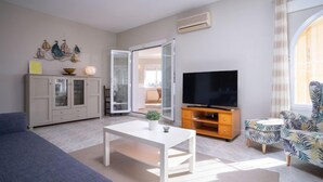 A modern living room with a sofa, a coffee table, a TV on a wooden stand, and a cabinet with decorative items. - Kalmias by Interhome (Moraira)