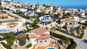 A residential area with a large house featuring a swimming pool, surrounded by well-maintained gardens and palm trees. - Kalmias by Interhome (Moraira)