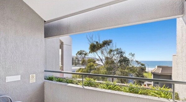 Een balkon met uitzicht op zee en bomen.