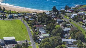 Vue aérienne d’un quartier résidentiel situé sur la côte, avec des maisons, une plage et un parking.