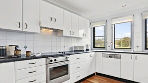 Une cuisine moderne avec des meubles blancs, une cuisinière en acier inoxydable et une machine à café.