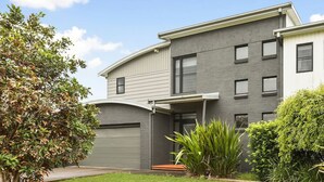 Un immeuble résidentiel moderne à deux étages, avec une façade grise, de nombreuses fenêtres et un allée couverte.
