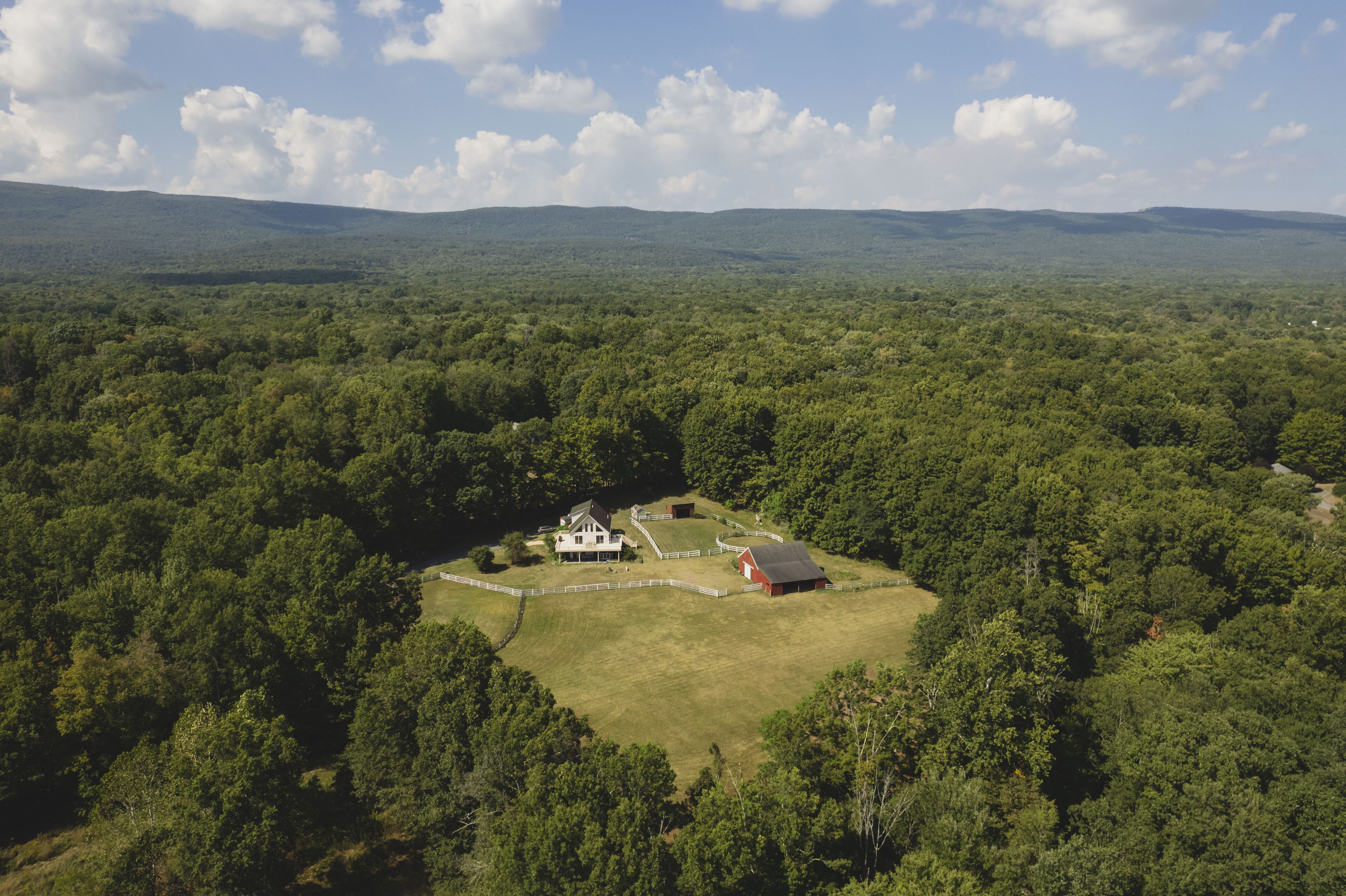 Un vaste domaine comprenant une maison principale, une grange et de vastes champs verdoyants.