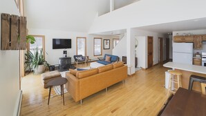 Een ruime woonkamer met een bank, een televisie en een open haard.