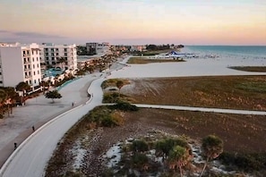 A coastal resort with a beachfront road, beach, and buildings with balconies.