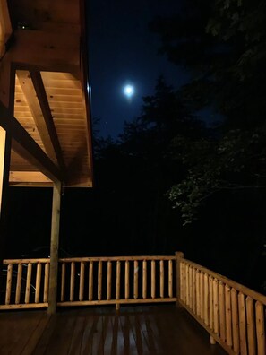 A wooden deck with a railing, a wooden structure with a sloped roof, and a full moon in the background. - NEWER cabin, 5 BR, 2 fireplaces, hot tub, privacy (Logan)