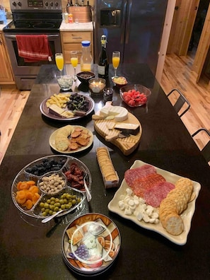 A well-organized buffet table with various food items and drinks. - NEWER cabin, 5 BR, 2 fireplaces, hot tub, privacy (Logan)