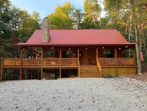 A wooden cabin with a red roof, a covered porch, and a chimney. - NEWER cabin, 5 BR, 2 fireplaces, hot tub, privacy (Logan)