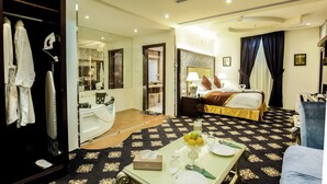 A hotel room with a bed, a sitting area with a table, and a bathroom with a mirror and shower.