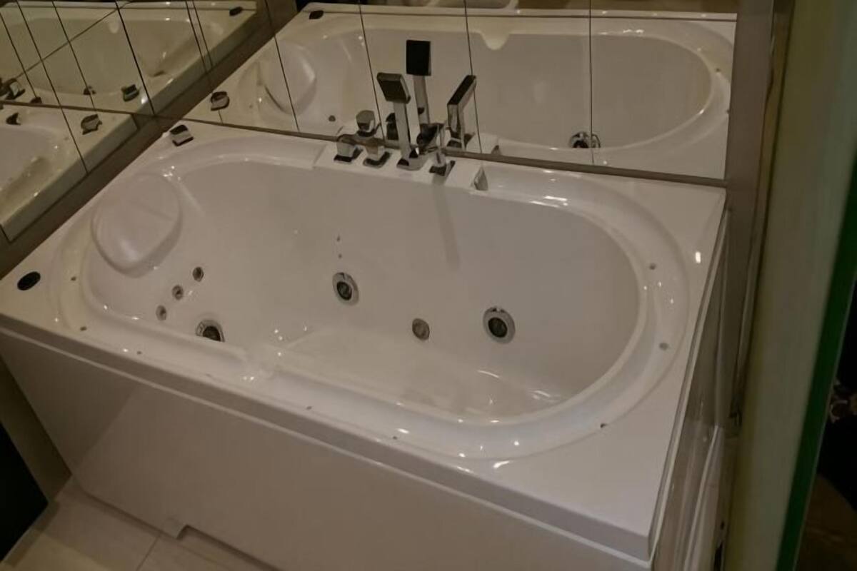 A large, white, freestanding bathtub with multiple faucets and a control panel.