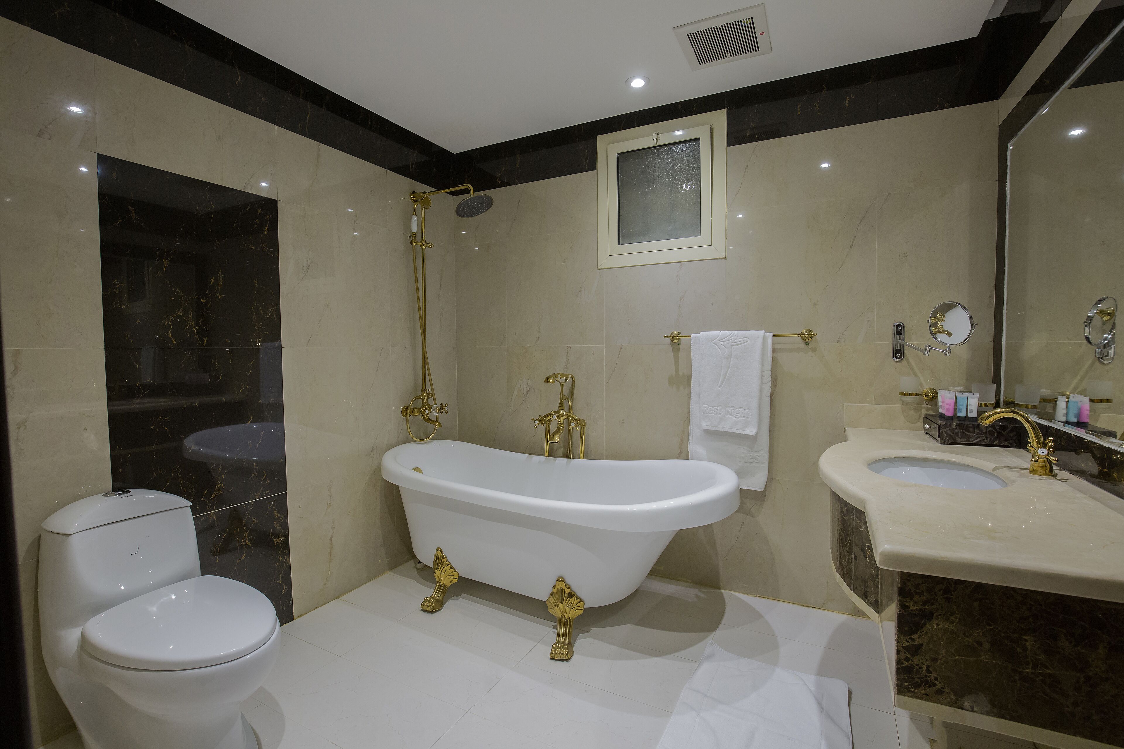 A bathroom with a freestanding bathtub, a toilet, a sink, and a mirror.