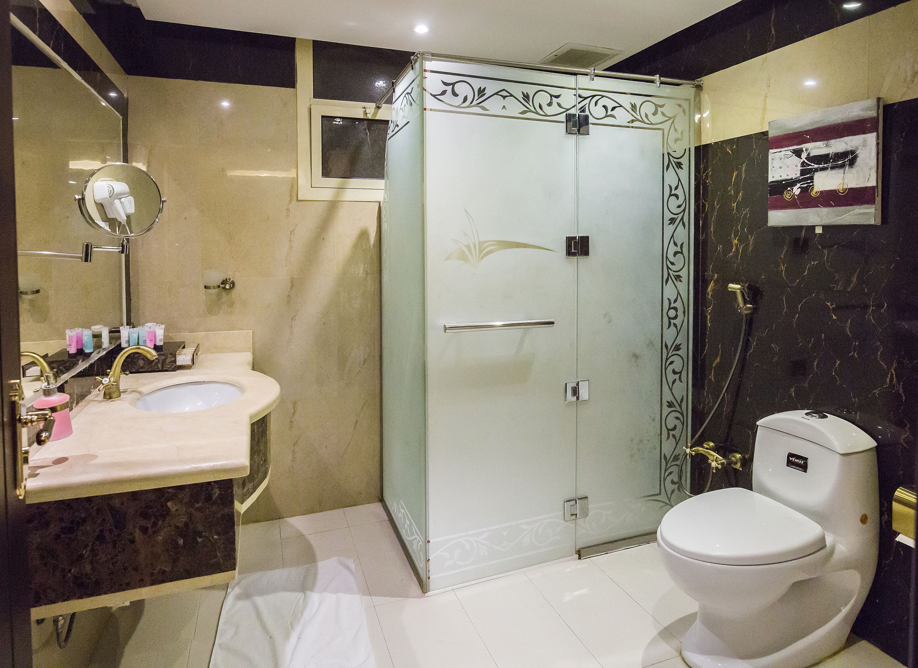 A bathroom with a glass-enclosed shower, a toilet, and a sink with a mirror.