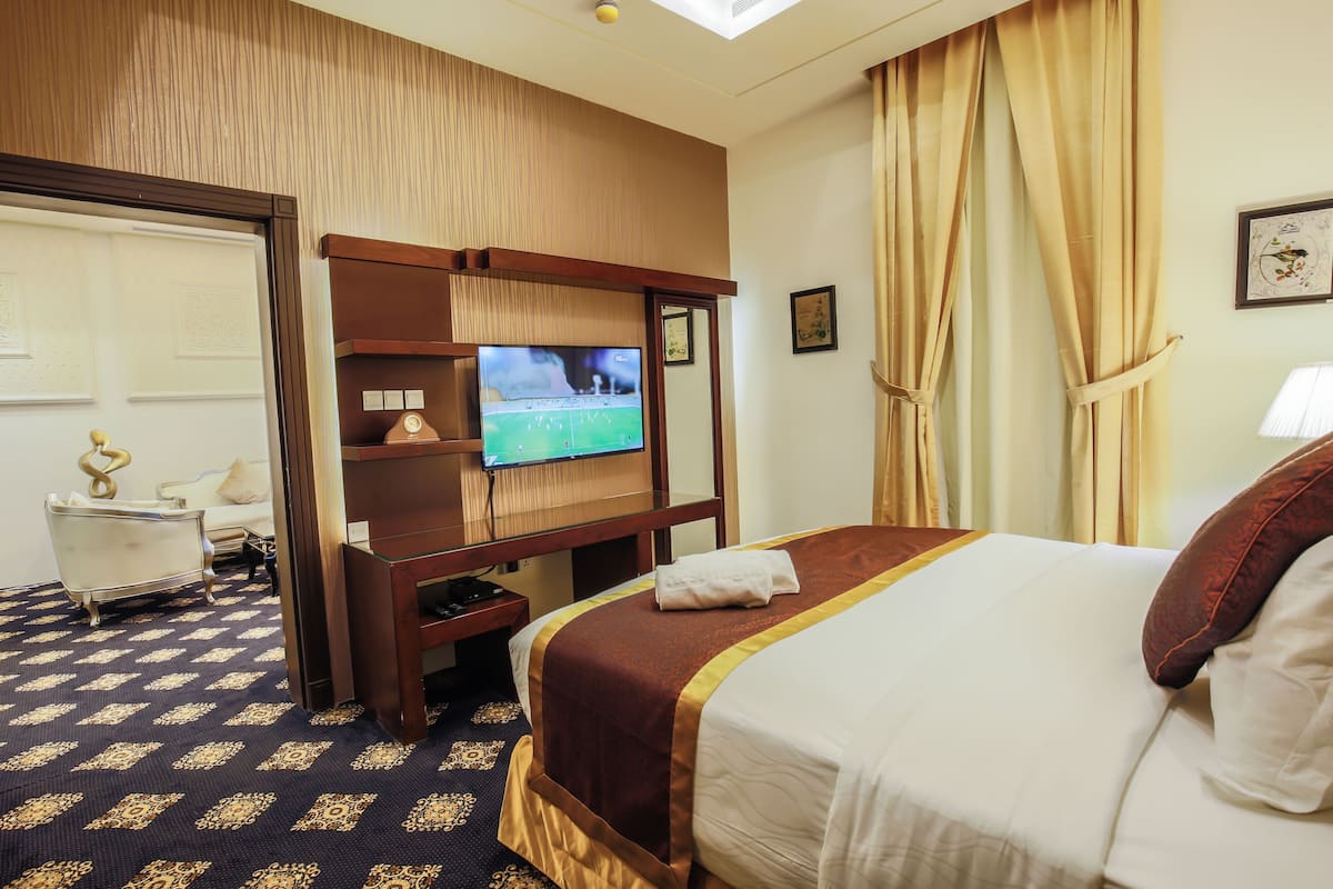 A hotel room with a bed, a television, a desk, and a chair.