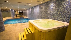 A spa area with a hot tub, a small pool, and wooden benches.
