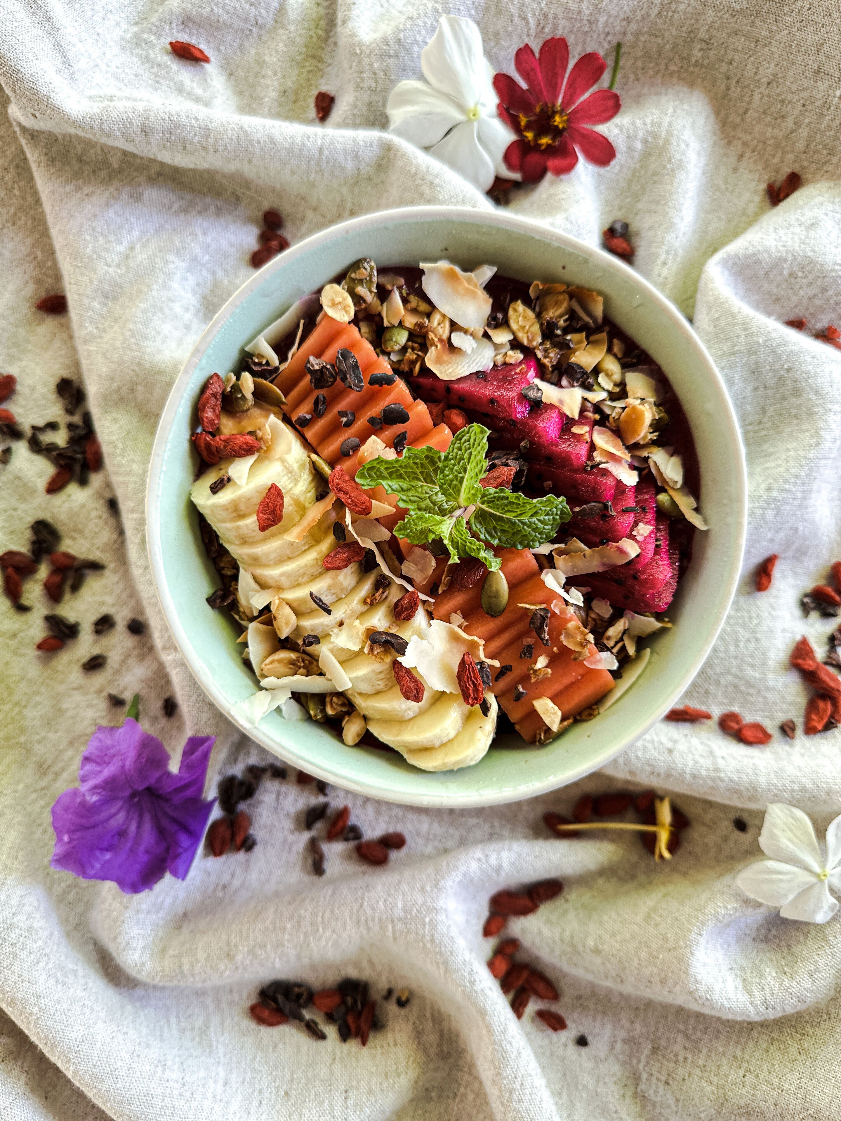 A bowl of food with various toppings, placed on a cloth with flowers.