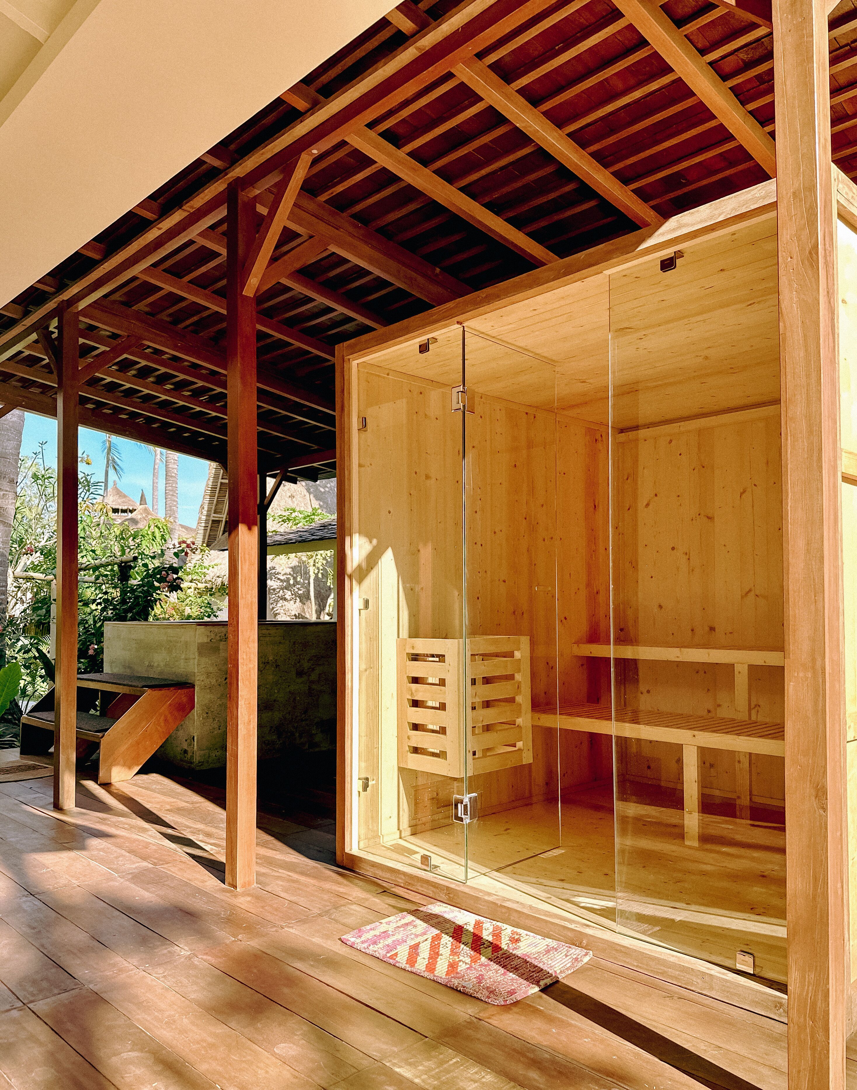 Une pièce en bois avec une porte en verre, un banc en bois et une petite armoire en bois.