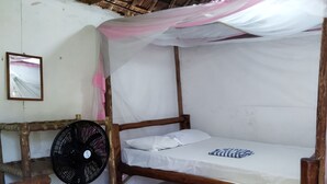 A rustic room with a wooden bed, a woven chair, a standing fan, and a framed picture on the wall. - Mida Creek Eco Camp - relax in cosy cottage (Mida)