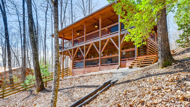 A wooden cabin with a balcony, surrounded by trees and a leaf-covered ground. - Hot Tub + Fire Pit: Dog-Friendly Cabin in Murphy! (Murphy)