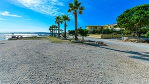 A beach with palm trees, a yellow building, and a clear blue sky. - Seafront Holiday Apartment Inga with sea view (Vir)
