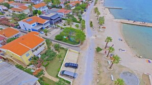 An aerial view of a coastal residential area with houses, a beach, and a pier. - Seafront Holiday Apartment Inga with sea view (Vir)