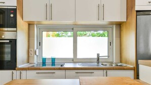 A modern kitchen with white cabinets, a double sink, and a window above the sink. - Seafront Holiday Apartment Inga with sea view (Vir)