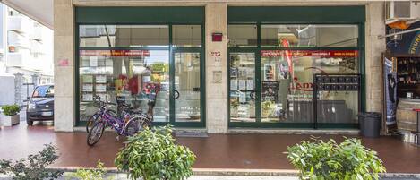 A tourist agency named 'Lampo' with a green and white sign, a bicycle parked outside, and potted plants in front.