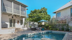 A swimming pool with a stone deck, outdoor furniture, and a covered seating area.