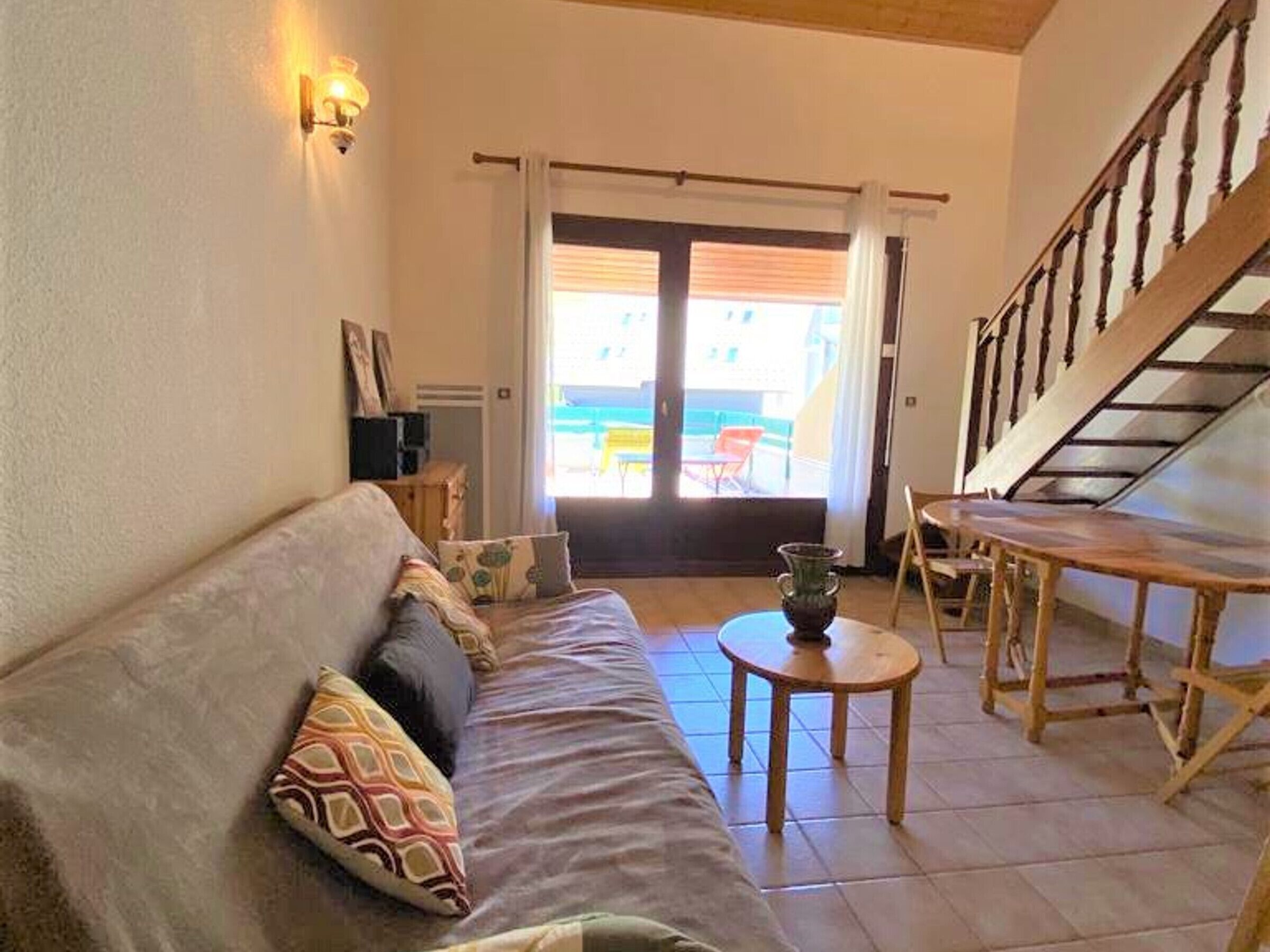 A living room with a sofa, a small table, and a staircase.