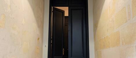 A staircase with a black door at the top, leading to a room with a white ceiling and a light fixture.