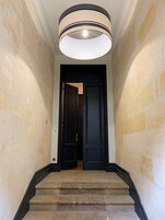 A staircase with a black door at the top, leading to a room with a white ceiling and a light fixture.