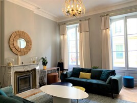 A living room with a fireplace, a sofa, a round table, and a chandelier.