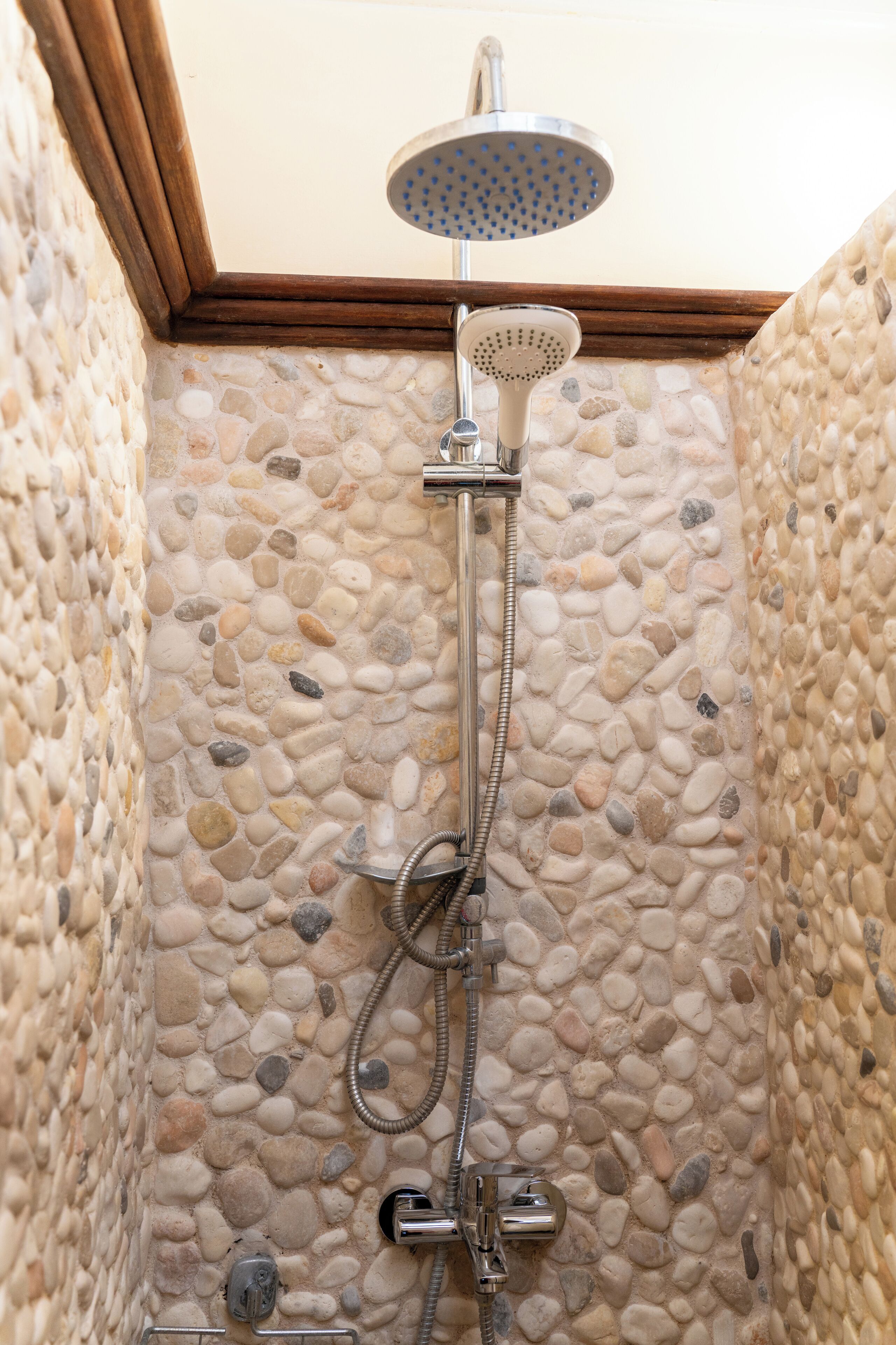 A shower with a handheld showerhead and a wall-mounted faucet.