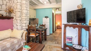 Una sala de estar acogedora con pared de piedra, una mesa de comedor de madera y un televisor sobre un mueble de madera.