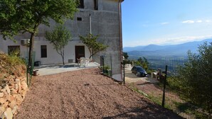 A two-story building with a gravel driveway, a fenced area, and a view of distant mountains.