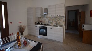 A modern kitchen with white cabinets, a tiled backsplash, and a stainless steel range hood.