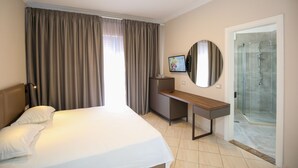 A hotel room with a bed, a desk, a TV, and a shower area. - Hotel Regina Garden Vlore (Vlorë)
