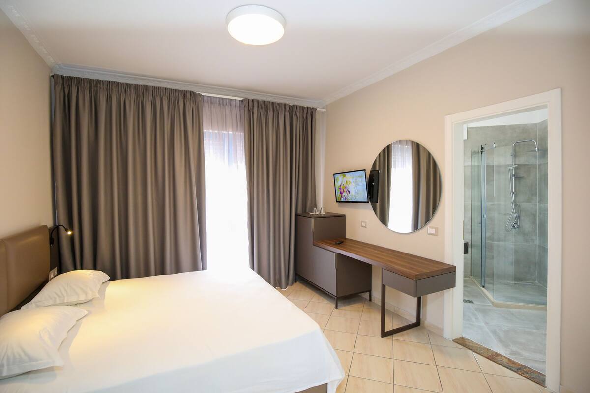 Une chambre d’hôtel équipée d’un lit, d’un bureau, d’une télévision et d’un espace douche.