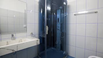 Een badkamer met een douche met glazen wand, een marmeren wastafel en een wit toilet.