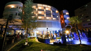 The exterior of the Regina Garden Hotel with a well-lit facade, outdoor seating area, and a landscaped garden. - Hotel Regina Garden Vlore (Vlorë)