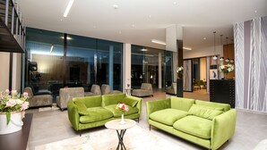 A modern living room with green sofas, a round coffee table, and a vase of flowers. - Hotel Regina Garden Vlore (Vlorë)