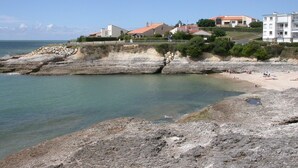 Une zone côtière caractérisée par un terrain rocheux, une plage et des immeubles résidentiels.