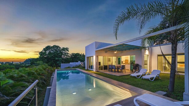 Una casa moderna con piscina, mobiliario exterior y vistas al paisaje.
