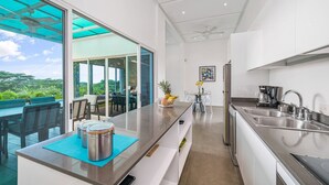 Una cocina moderna con una isla grande, electrodomésticos de acero inoxidable y vistas al exterior.