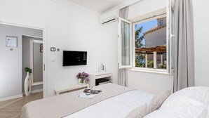 Una habitación de hotel moderna con una cama grande, un televisor de pantalla plana, un escritorio pequeño con una computadora y una ventana con vista al exterior.