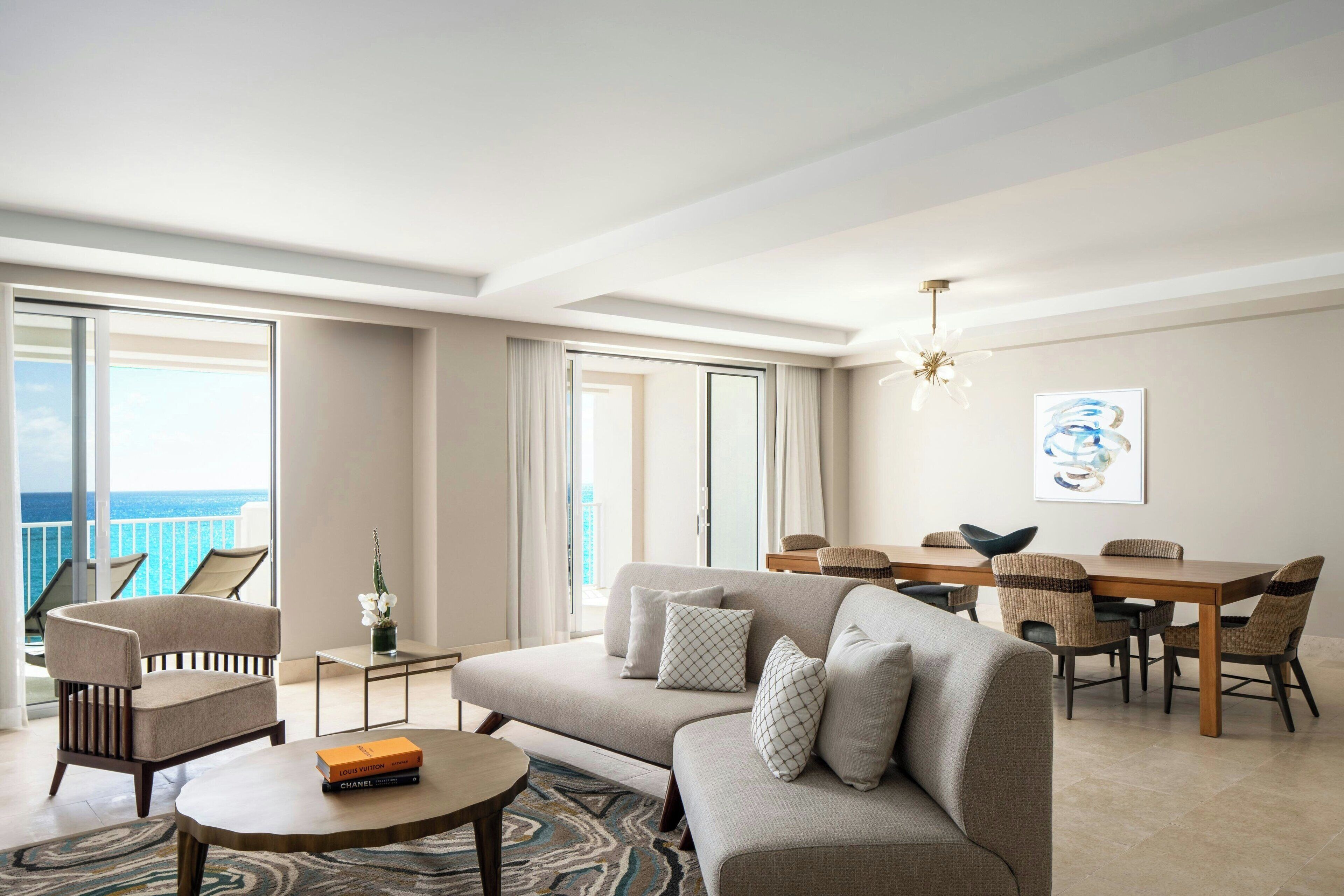 Una sala de estar moderna con sofá, sillones, una mesa de centro y una zona de comedor con mesa y sillas.