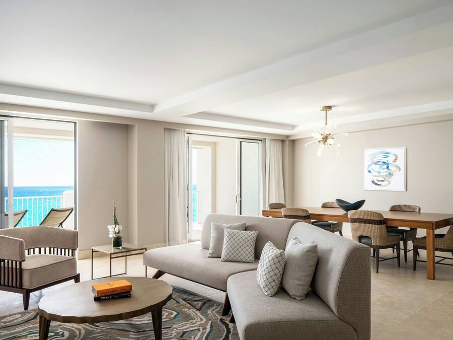 Un salon moderne comprenant un canapé, des fauteuils, une table basse et un coin repas avec une table et des chaises.