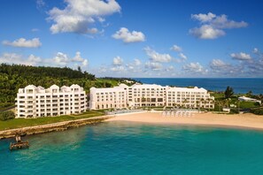 A large, multi-story hotel with a beach and ocean view, featuring a pool and multiple balconies.