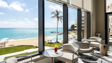 A balcony with a view of the beach and ocean, furnished with chairs and a table.