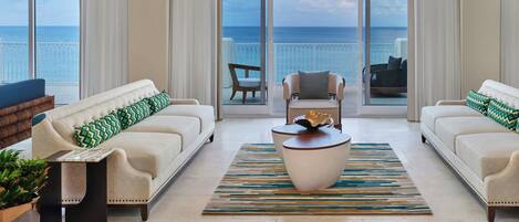 A spacious living room with two sofas, a coffee table, and a large window offering a view of the ocean.