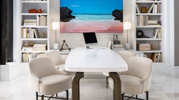 Una sala de estar moderna con un televisor de pantalla plana grande, sillones color beige y una mesa de centro blanca.